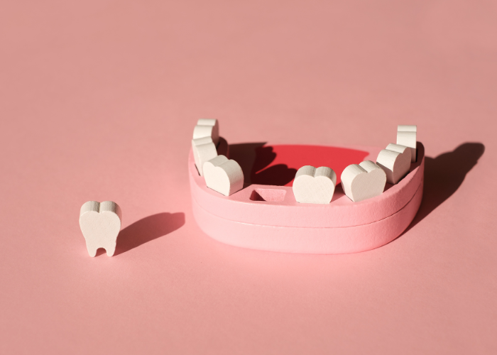 Image of a model of teeth and gums on a pink background, representing dental prosthetics or orthodontic models.